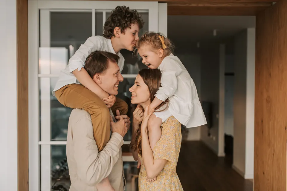 Parents sharing a playful moment with their two children at home.